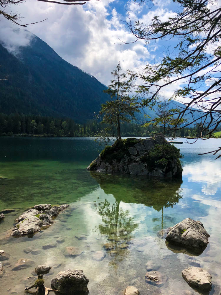Hintersee im Zauberwald bei Berchtesgaden. Der See spiegelt die gegenüberliegenden Berge sowie Bäume und Wolken.