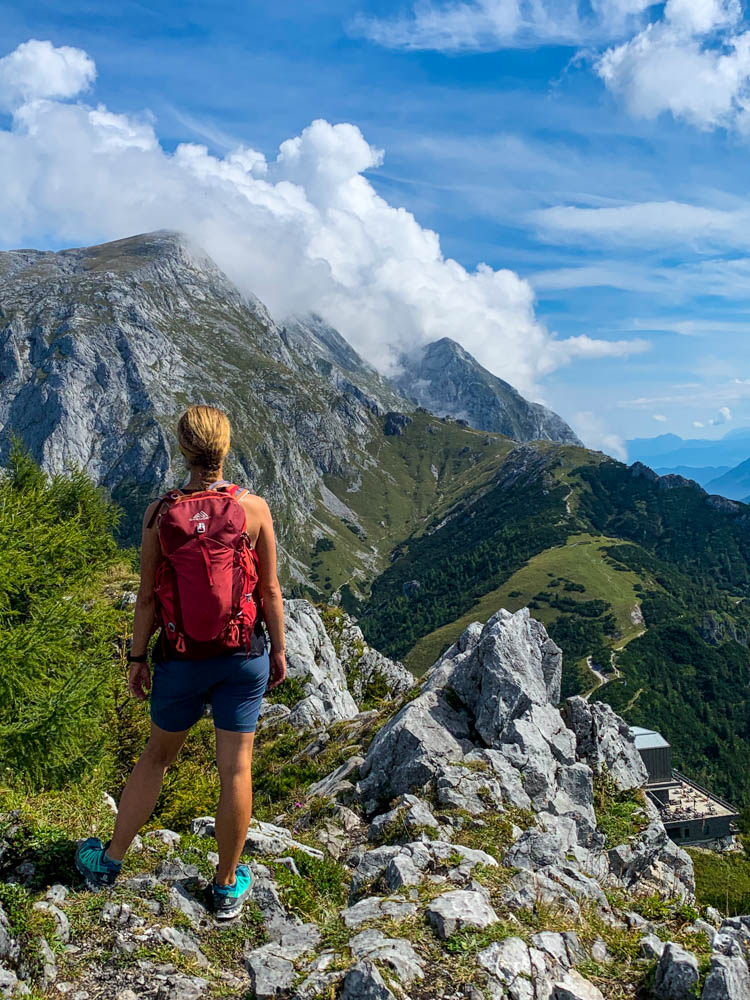 Melanie blickt auf die Berchtesgadener Alpen vom Gipfel des Jenner aus. Tolle Berglandschaft mit ein paar wenigen Wolken über den Gipfeln.