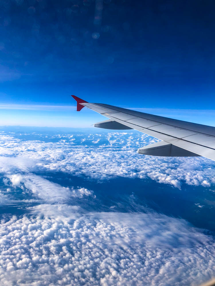 Blick aus dem Flugzeug auf einen Flügel des Flugzeugs. Wolkenmeer unten, blauer Himmel oben
