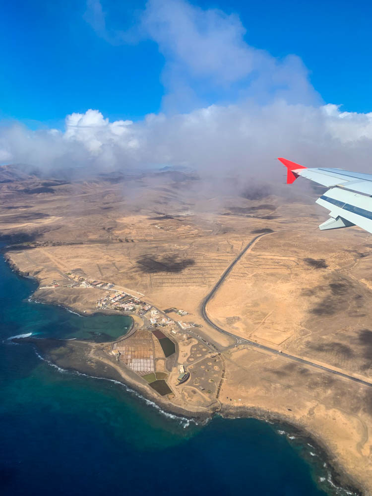 Blick aus dem Fenster eines Flugzeugs. Es ist die Küste von Fuerteventura zu sehen sowie ein Stück eines Flügels des Flugzeugs