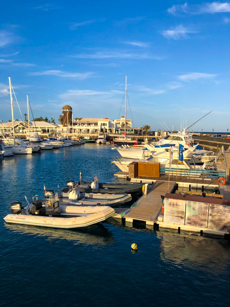 Hafen in Caleta de Fuste Fuerteventura. es ist ein Teil der Tauchbasis zu sehen mit Booten und Pool. Der Himmel ist kräftig blau