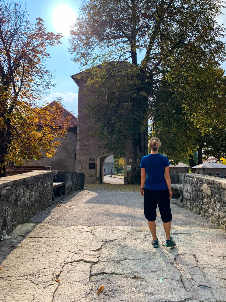 Melanie steht auf einer Brücke und blickt Richtung einem Torbogen. Dorf entdeckt bei Roadtrip Slowenien