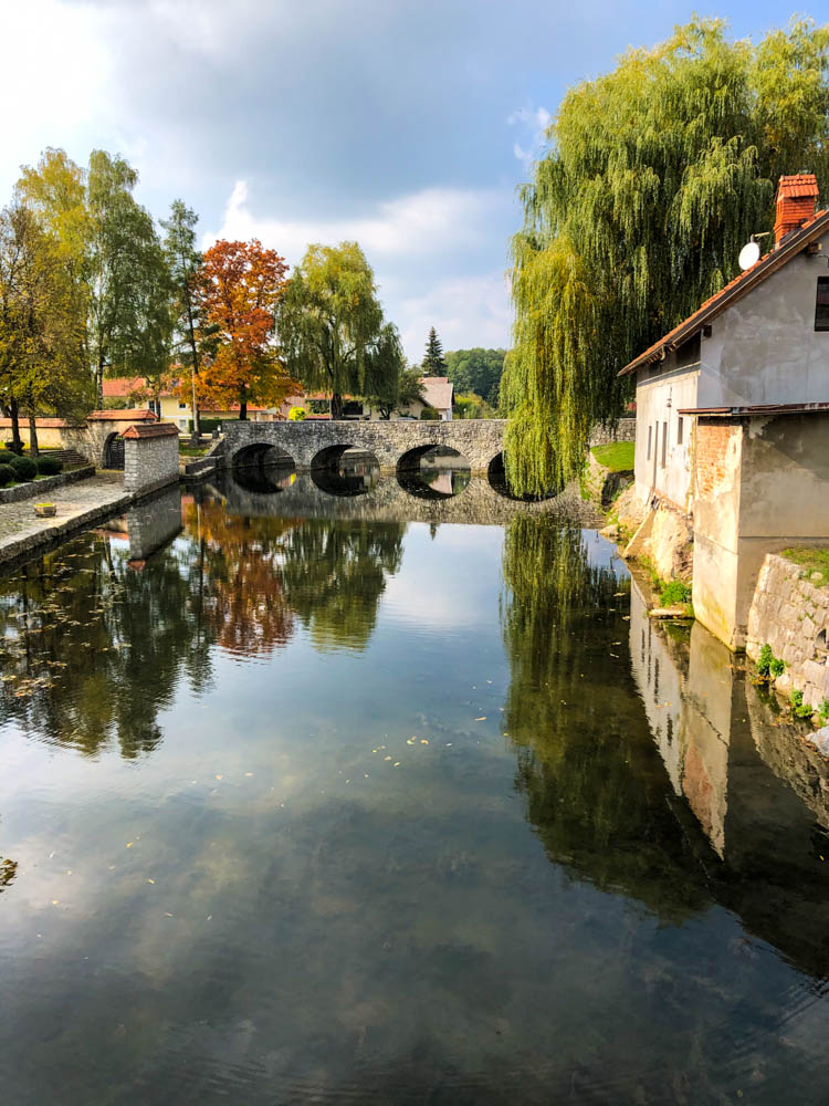 Roadtrip Slowenien - Brücke, Bäume und Häuser spiegeln sich in einem Fluss