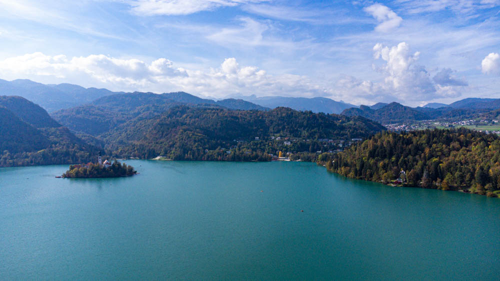 See Bled von oben fotografiert. Die Berge und Bäume auf der anderen Seite des Sees sind zu sehen. In der Mitte des Sees ist eine Insel. Roadtrip Slowenien