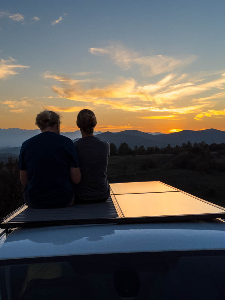 Melanie und Julian sitzen auf der Dachterrasse von Van Vivaldi und genießen den Sonnenuntergang.