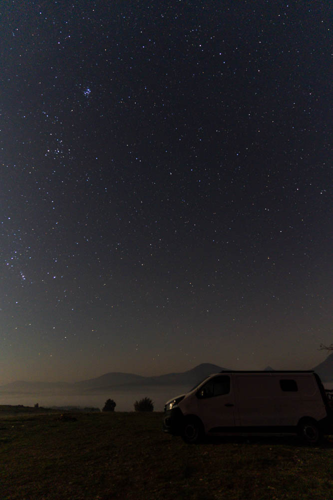 Nachtaufnahme Van Vivaldi - Sternenfotografie Kroatien. Über dem Van sind etliche Sterne zu sehen sowie am Horizont ein paar Bergkonturen.