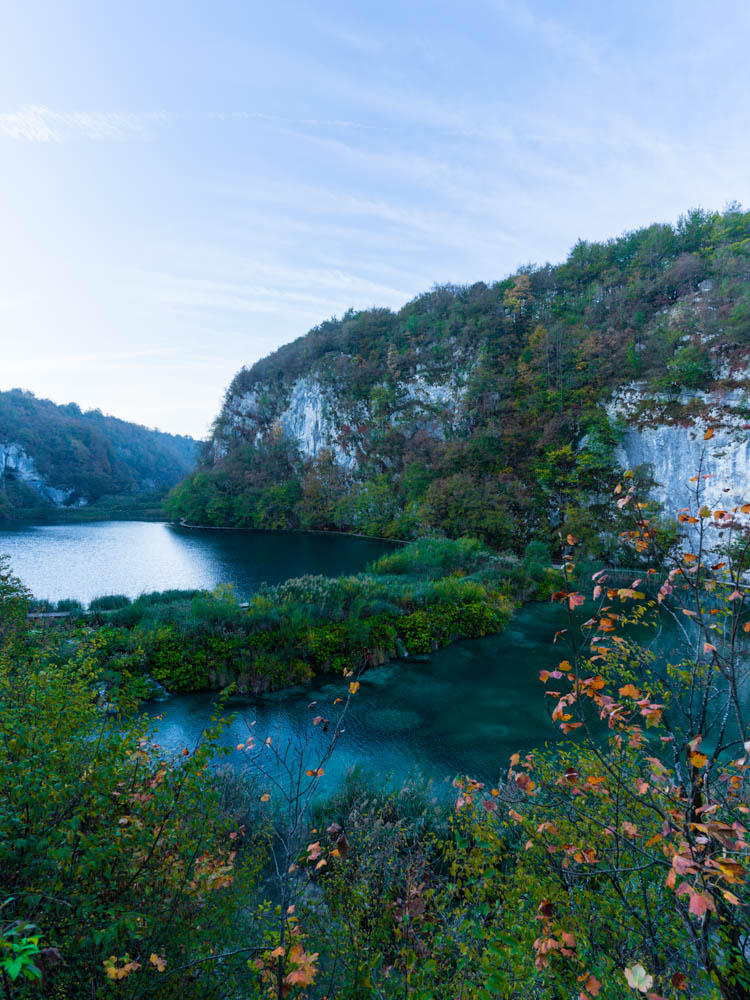 Morgenstimmung Nationalpark Plitvicer Seen in Kroatien. Blick von oben auf zwei Seen, eine Felswand sowie viel grüne Natur.