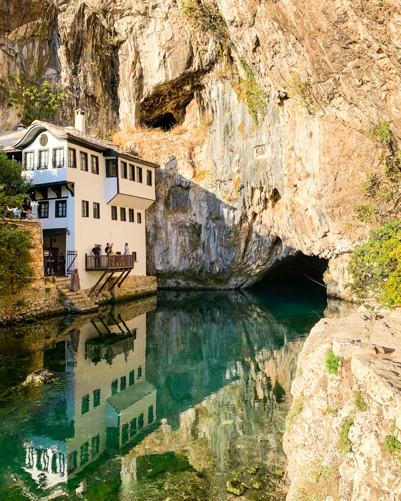 Derwischkloster in Blagaj in Bosnien und Herzegowina. Es ist zudem die Quelle Vrelo Bune zu sehen. Das Kloster spiegelt sich im Fluss, welcher aus der Höhle entspringt.