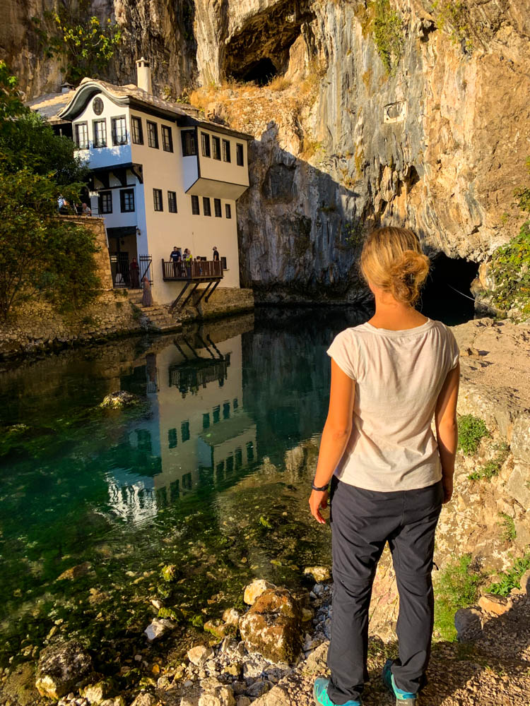Melanie blickt auf das Derwischkloster in Blagaj in Bosnien und Herzegowina. Es ist zudem die Quelle Vrelo Bune zu sehen. Das Kloster spiegelt sich im Fluss, welcher aus der Höhle entspringt.