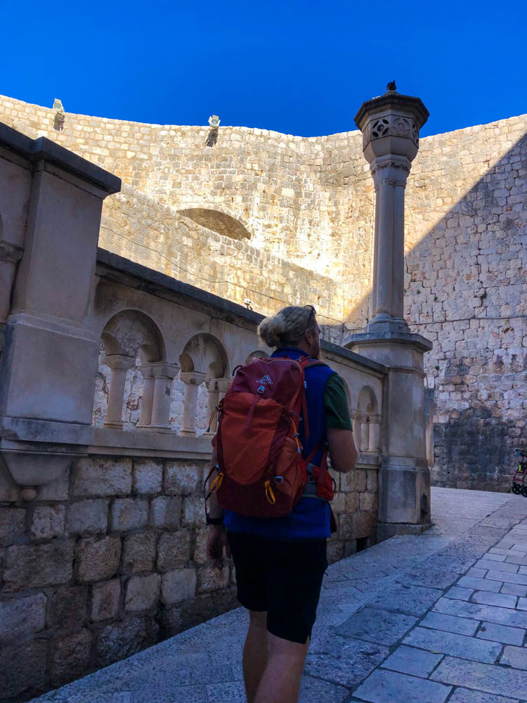 Julian läuft entlang der Stadtmauer in Dubrovnik Kroatien. Der Himmel ist kräftig blau