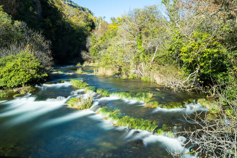 Langzeitbelichtung vom Fluss. Das Wasser ist verschwommen und zieht weich durch die grüne Landschaft. Krka Nationalpark Kroatien