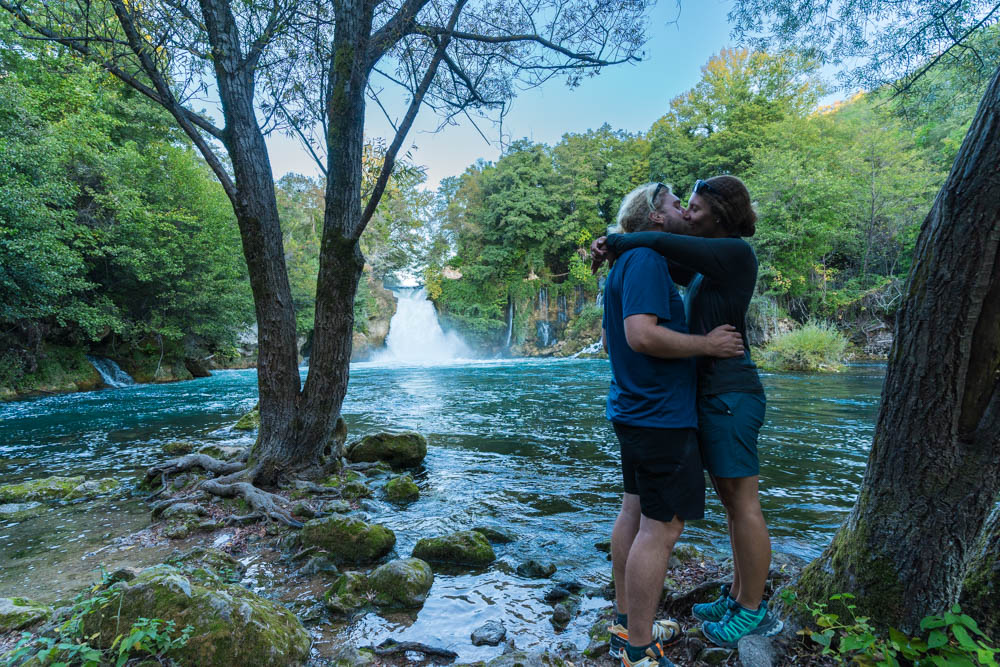 Melanie und Julian stehen vor einem Wasserfall und küssen sich. Krka Nationalpark Kroatien