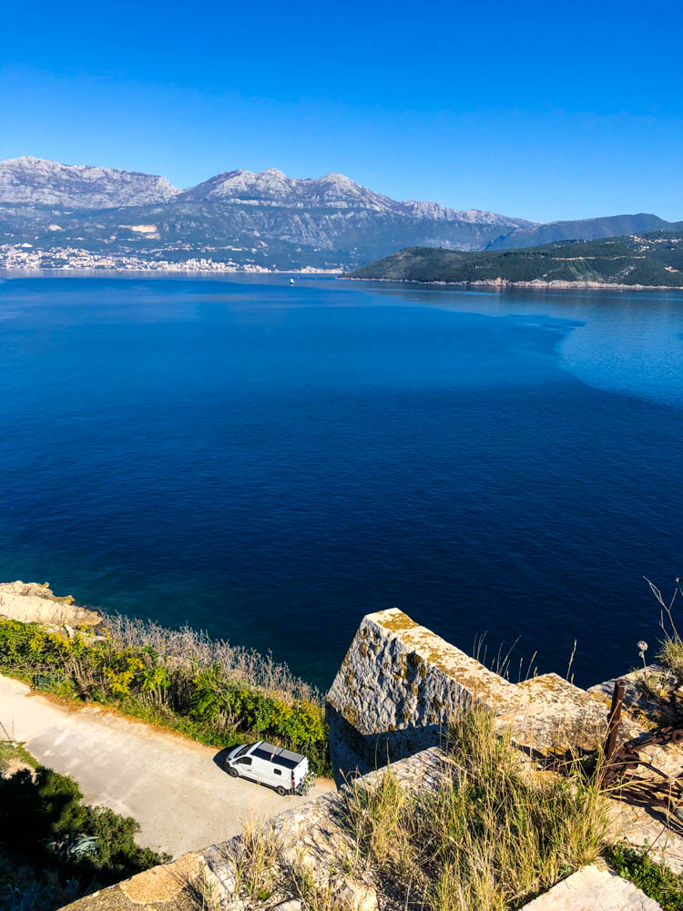 Blick von verlassenen Burganlage auf Van Vivaldi, welcher etwas weiter unten parkt, sowie Kroatien. Das Meer ist kräftig blau, genauso wie der Himmel