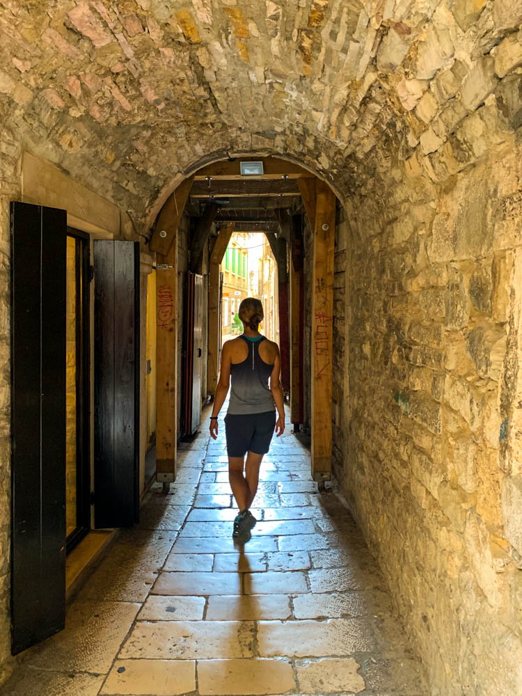 Melanie läuft durch eine schmale Stadtmauer in Split