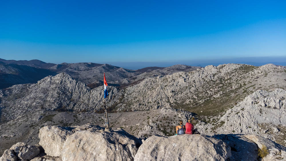 Wir sitzen am Gipfel des Tulove Grede in Kroatien und schauen in der Ferne. Die Kamera ist hinter uns und schaut gemeinsam mit uns auf das gewaltige Panorama.