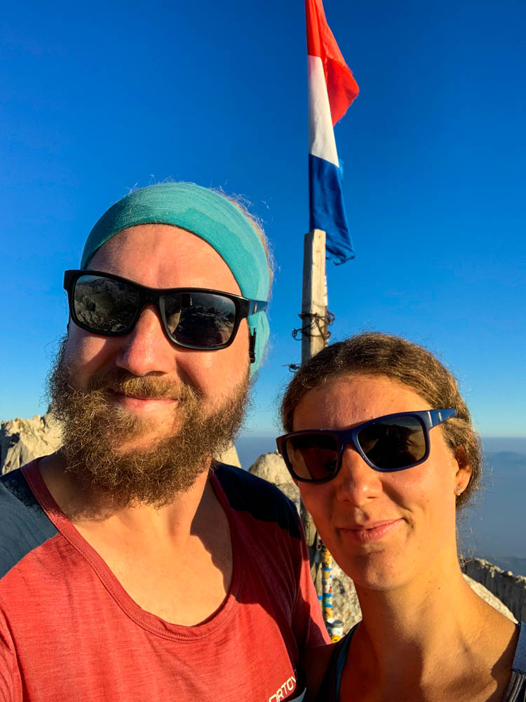 Selfie vor der Gipfelfahne. Beide mit Sonnenbrille und einem breiten grinsen.