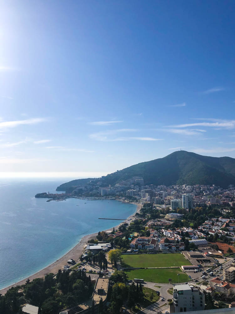 Blick von einem Pass auf Budva in Montenegro. Der Himmel ist kräftig blau, das Meer ist im linken Teil des Bildes zu sehen.