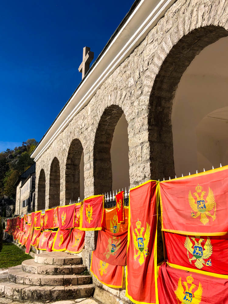 Kloster in Cetinje mit einigen Flaggen Montenegros davor. Der Himmel ist kräftig blau.