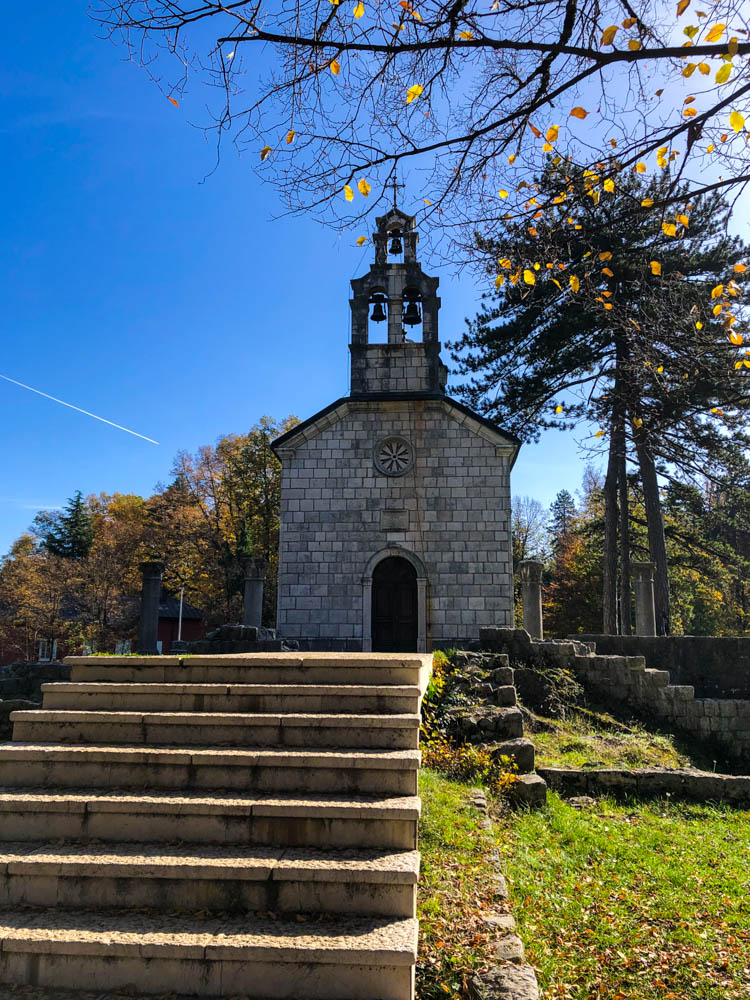 Kleine Kapelle in Cetinje mitten in einem Park umgeben von viel grün. Der Himmel ist kräftig blau.