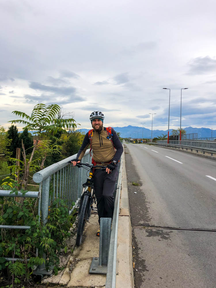 Julian schiebt sein Fahrrad auf einem ziemlich schmalen Stück neben der Hauptstraße in Montenegro. Fahren war unmöglich. Er grinst in die Kamera