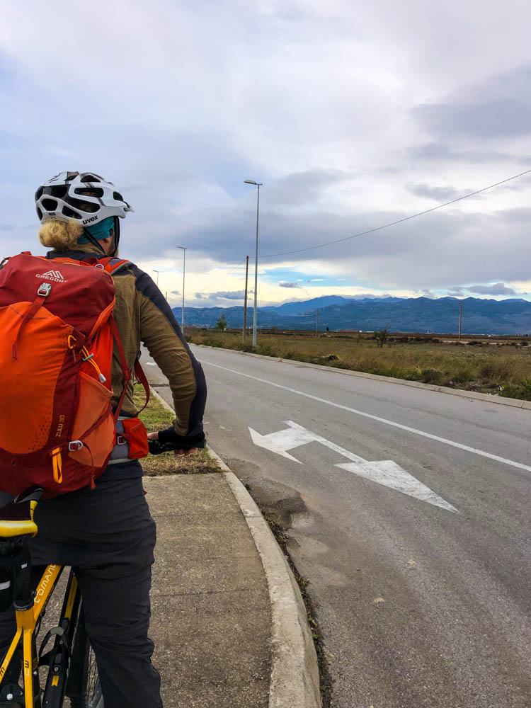 Julian blickt in die Ferne und hebt dabei sein Fahrrad fest. Bergwelt Montenegros