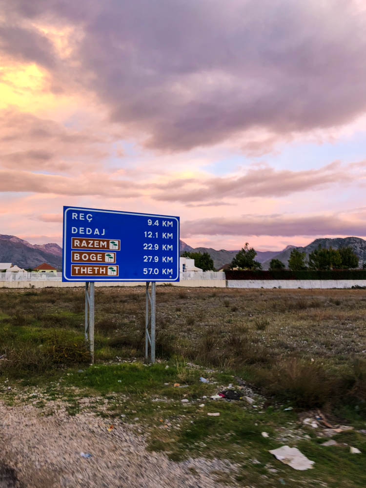 Schild am Straßenrand in Albanien, auf welchem Kilometerangaben gezeigt werden. Bis nach Theth sind es noch 57 Kilometer.