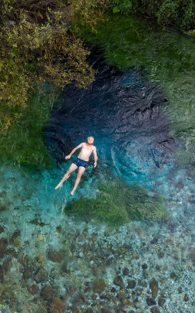 Julian im Wasser bei Blue Eye in Südalbanien. Er liegt flach im Wasser und wird von der Strömung davon getragen. Aufnahme von oben
