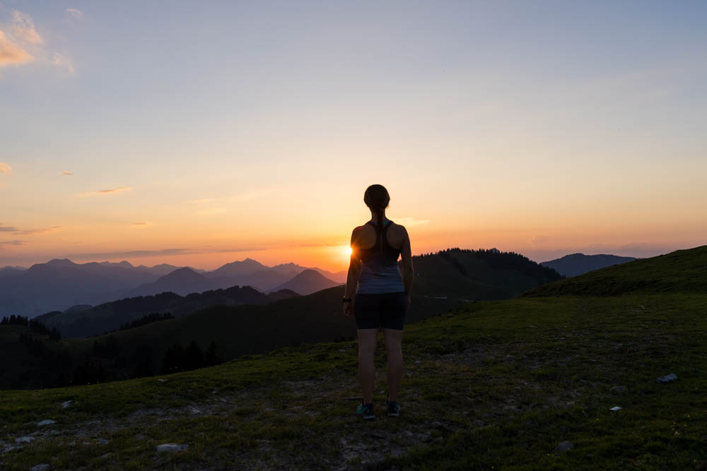 Melanie blickt in die Ferne auf eine herrliche Bergkulisse. Sonnenuntergang in den Chiemgauer Alpen