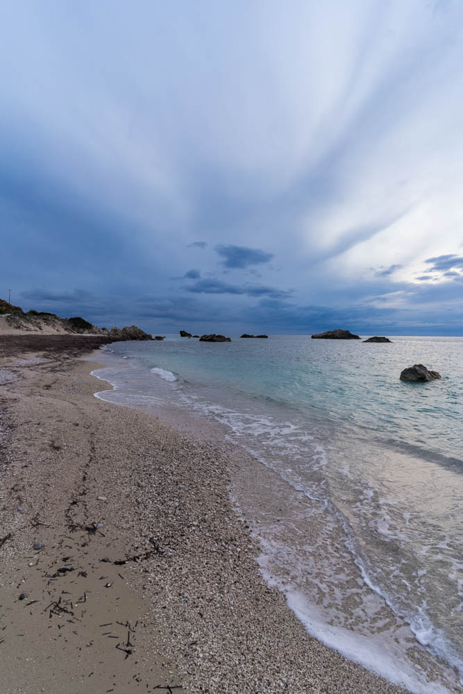 Strand auf Insel Lefkada in Griechenland mit leichtem Wolkenschleier am Himmel. Rechts vom Bild ist das Meer zu sehen.