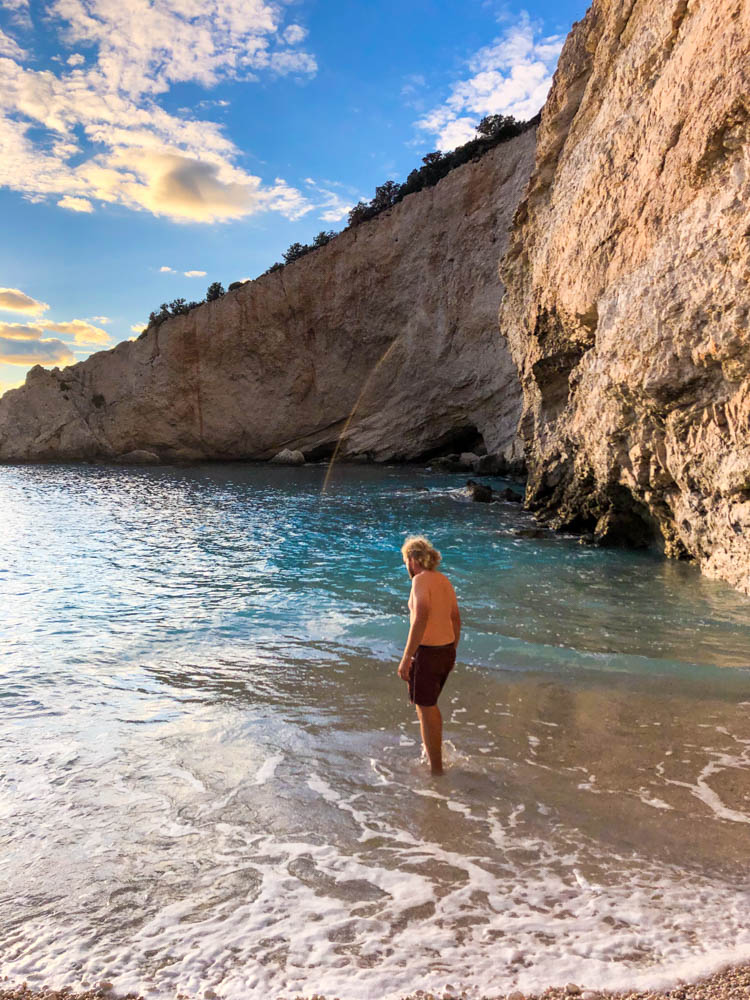 Julian läuft ins Meer, um baden zu gehen. Zur Ruhe kommen auf Lefkada in Griechenland in traumhaft schöner Strandbucht.