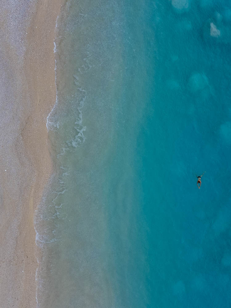 Melanie schwimmt im türkisfarbenen Wasser des ionischen Meeres. Zur Ruhe kommen auf Lefkada - Vogelperspektive von Strand und Meer
