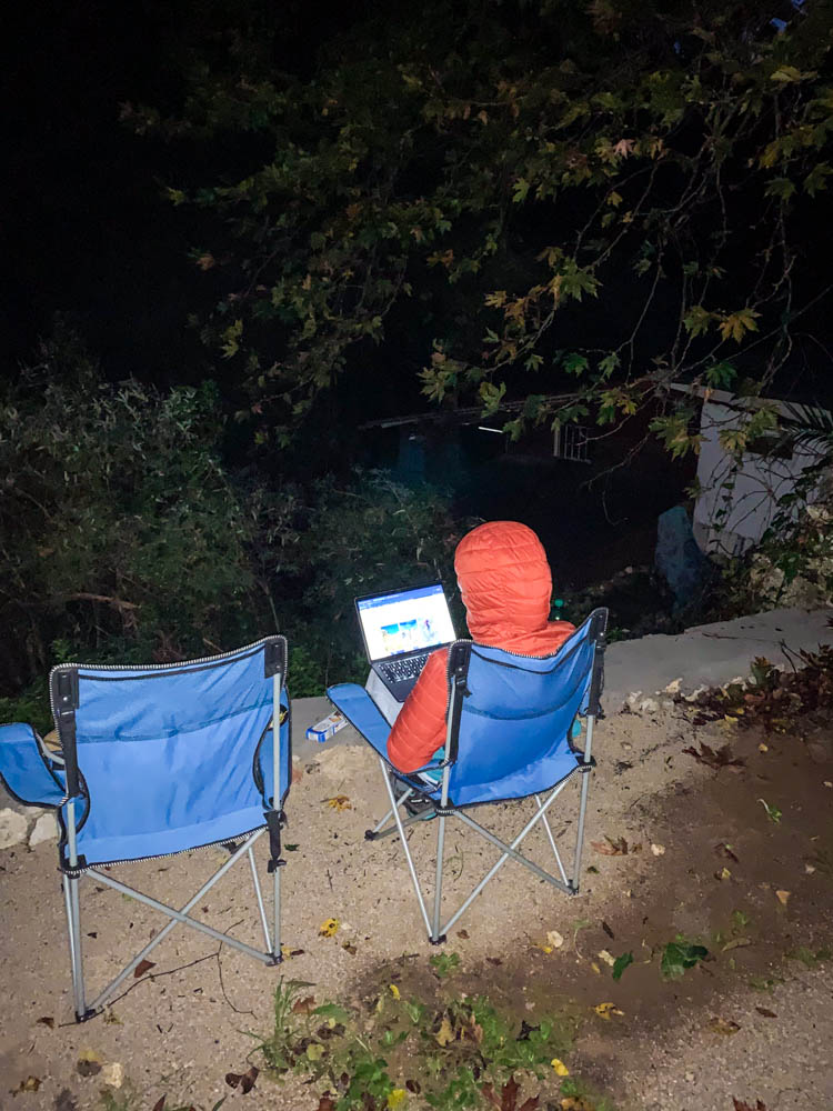 Melanie sitzt auf einem Campingstuhl im Dunkeln mitten in der Natur. Zur Ruhe kommen auf Lefkada und Arbeitsmodus.