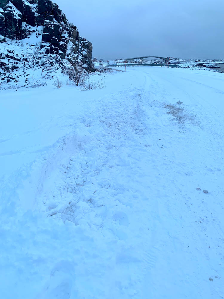 Straßenverhältnisse in Skandinavien im Winter. Im Schnee am Straßenrand sind Abdrücke eines Fahrzeugs zu erkennen, welches hier im Graben gelandet ist.