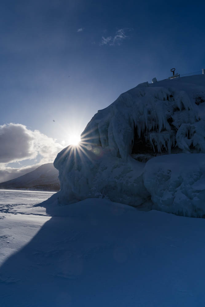 Sonnenstern im Abisko Nationalpark hinter Eisformation. Winter in Schweden