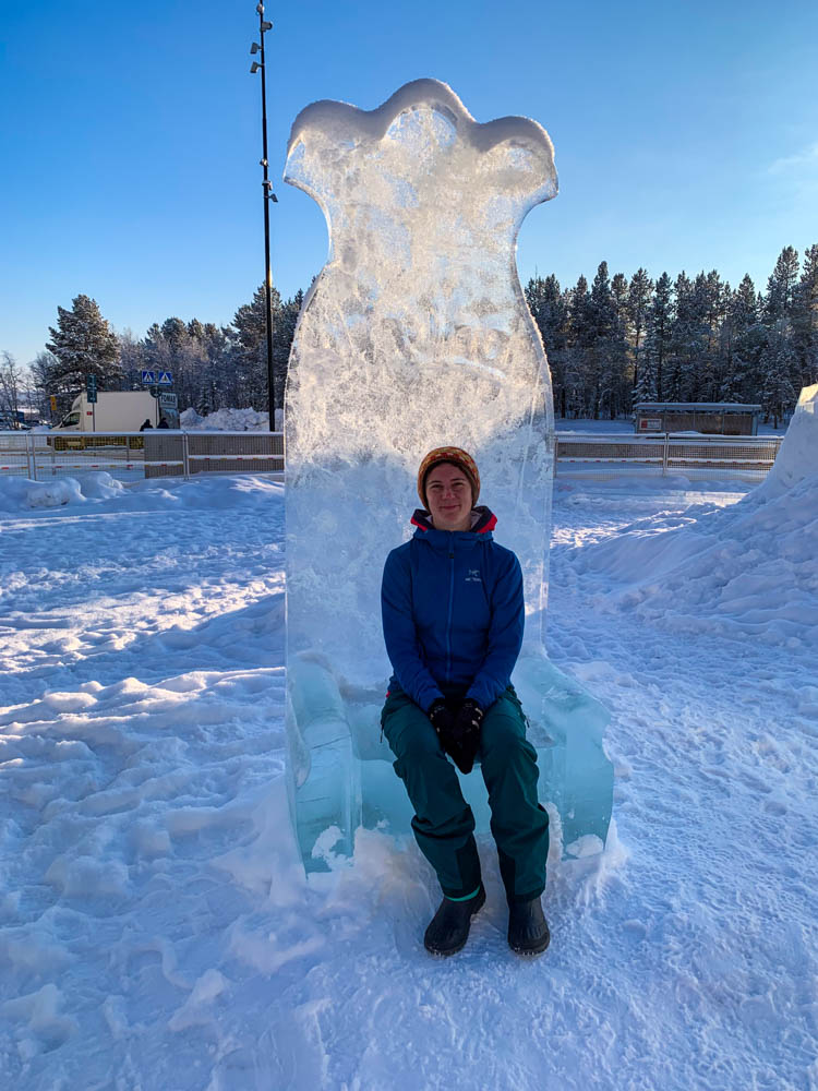 Melanie in Kiruna auf einem Thron aus Eis. Der Himmel ist kräftig blau. Winter in Nord Schweden - Sehenswerte Reiseziele