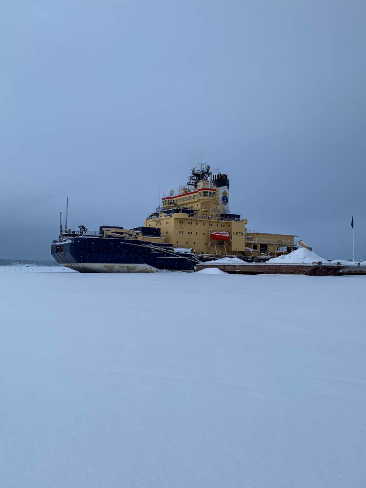 Eisbrecher in Lulea liegt im Eis. Davor ist viel Schnee zu sehen.