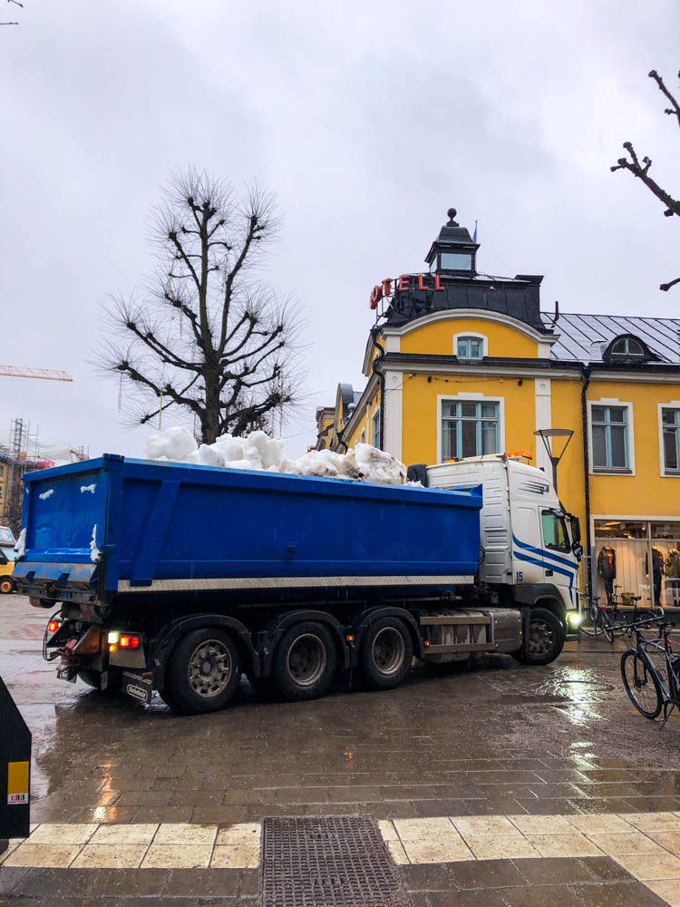 Örebro in Schweden - Ein LKW hat auf seinem Anhänger Schnee geladen, welcher am Dorfplatz abgeladen wird.