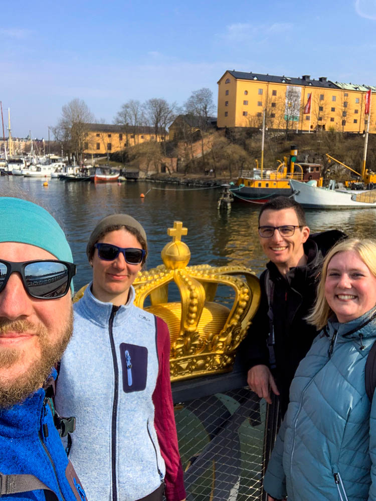 Selfie von Melanie und Julian mit ihrem Bruder und J. vor einer goldenen Krone an einer Brücke in Stockholm in Schweden