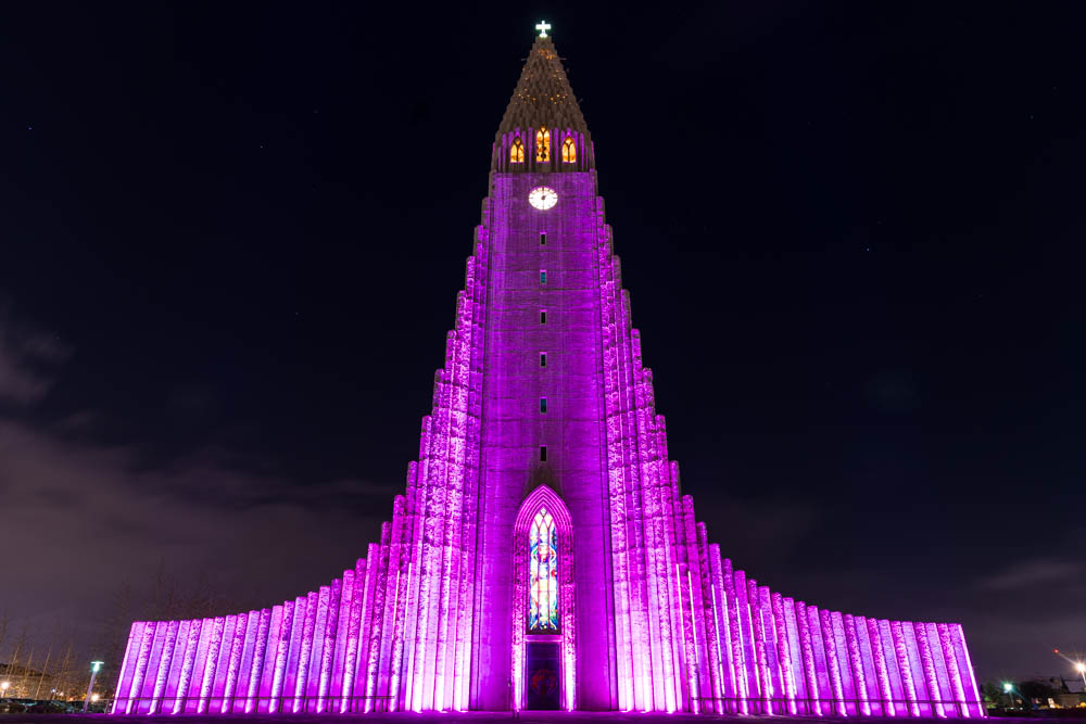 Hallgrímskirkja in der Hauptstadt Reykjavík, das größte Kirchengebäude Islands nachts lila beleuchtet. 5 Jahre Entscheidung zur Weltreise