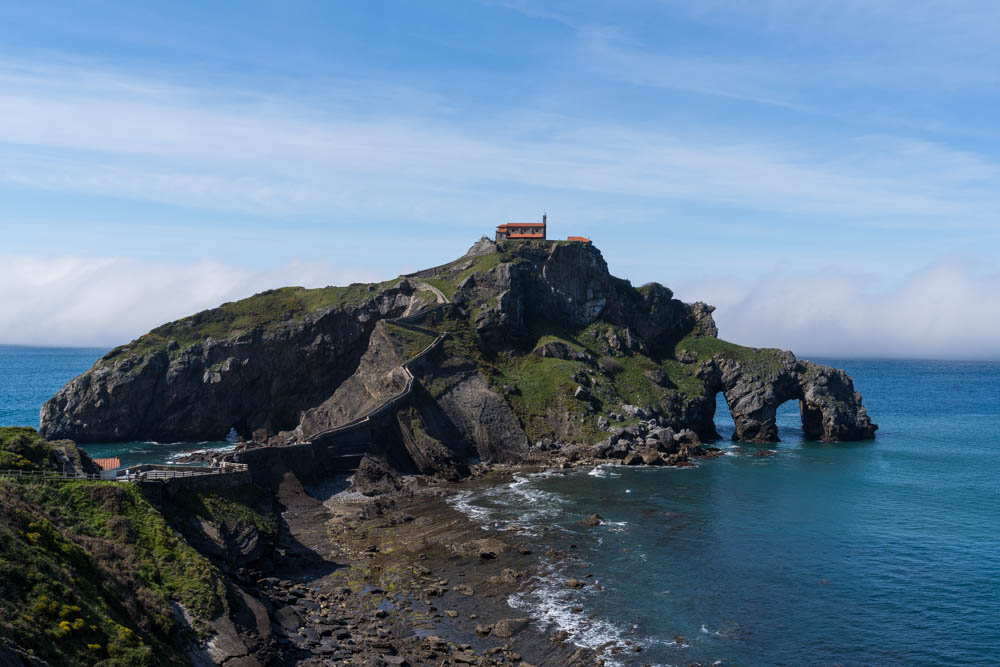 San Juan de Gaztelugatxe in Spanien durch Game of Thrones bekannt mit aufziehender Nebelfront über dem Meer. Kleine Kirche auf einer Insel im Meer, welche durch eine Steinbrücke zu erreichen ist.