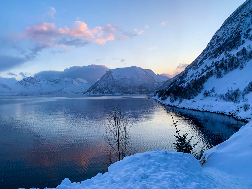 Sonnenuntergang in Fjord auf Senja, Norwegen. Winter Berglandschaft spiegelt sich leicht im Meer.