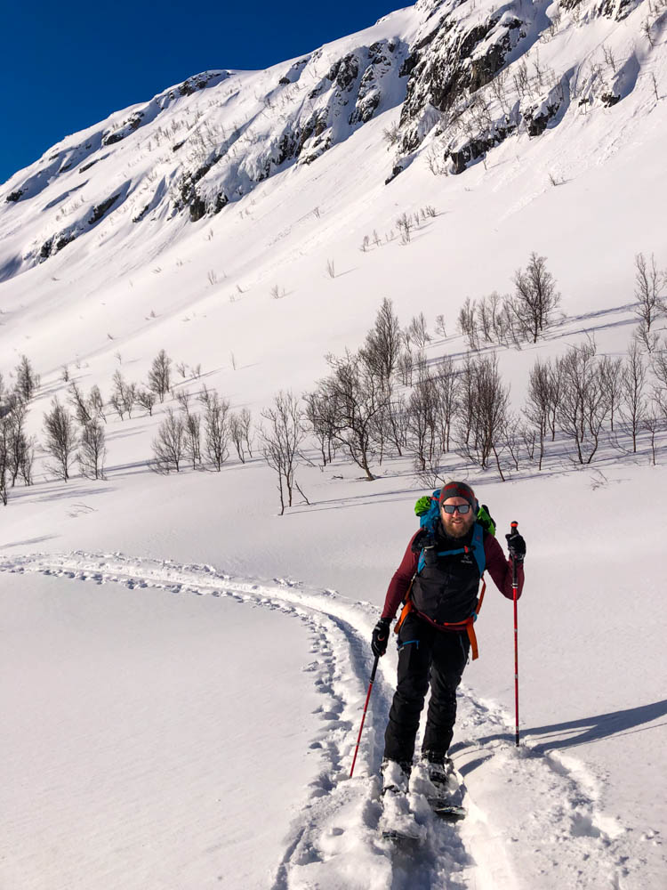 Julian im Aufstieg bei Tour mit den Splitboards. Schneelandschaft und blauer Himmel auf Senja, Norwegen