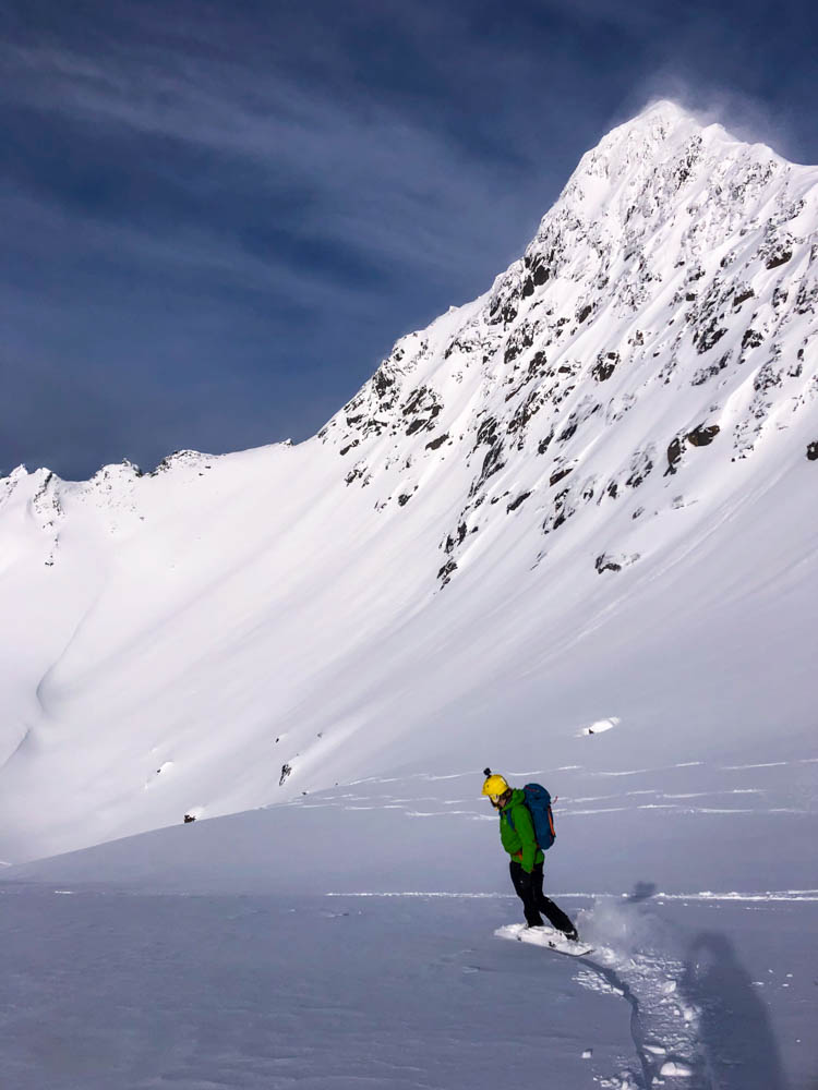 Julian bei Abfahrt mit Splitboard in verschneiter Berglandschaft. Tourengehen und Nordlichter auf Senja.