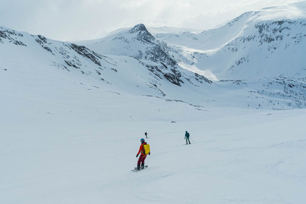 Melanie bei Abfahrt mit Splitboard auf Senja. Gemeinsame Skitour mit zwei Freunden im Winterparadies in Powder. Tourengehen und Nordlichter