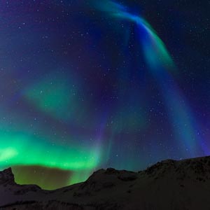 Blaue, violette und grüne Polarlichter über einer Bergkette in Senja, Norwegen. Sternenhimmel und Faszination Nordlichter