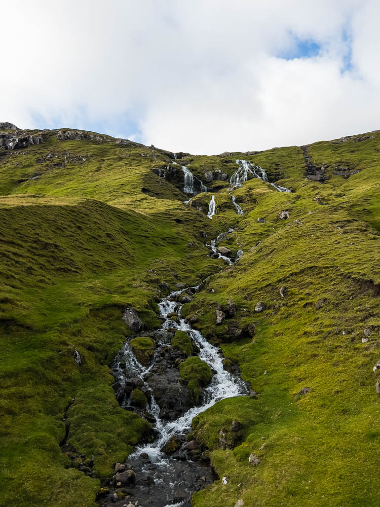 Wasserfall in grüner Landschaft Färöer