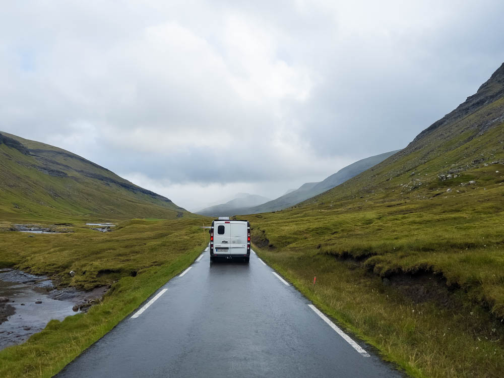 Van Vivaldi auf dem Weg nach Saksun auf den Färöer Inseln. Schmale Straße führt in den Talkessel, grüne Hügellandschaft. Mit dem Camper auf die Färöer Inseln