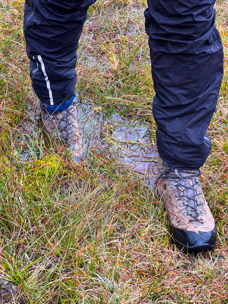 Julians Füße sind zu sehen. Wanderschuhe im Matsch und Sumpf der Färöer.