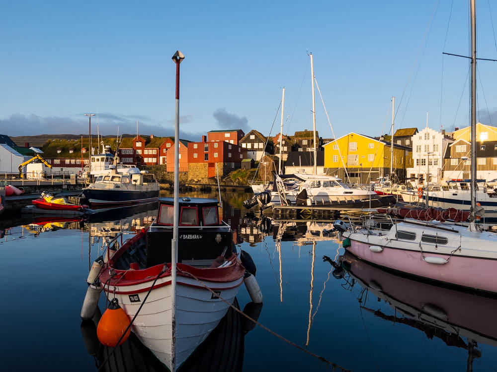 Hafen der Hauptstadt Tórshavn Färöer Inseln - es sind einige Boote im Wasser und dahinter wunderschöne, bunte Häuser zu sehen. Mit dem Camper auf die Färöer Inseln