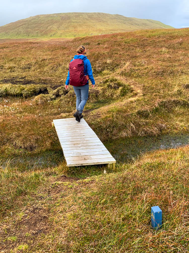 Melanie bei Wanderung auf Insel Nólsoy. Teils sumpfige Landschaft, die durch Stege überbrückt werden. Färöer Inseln mit dem Camper und zu Fuß erkunden